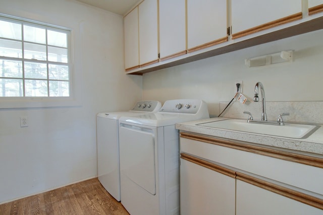 laundry room with sink, light hardwood / wood-style flooring, cabinets, and washing machine and clothes dryer