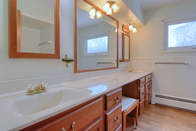 bathroom with baseboard heating, plenty of natural light, tile walls, and vanity