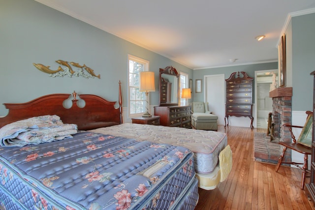 bedroom featuring ornamental molding, a fireplace, and light hardwood / wood-style floors