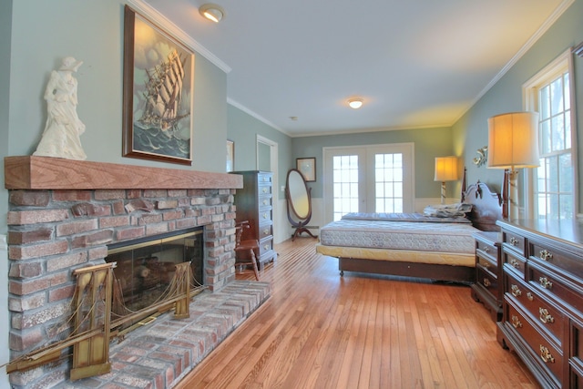 bedroom with multiple windows, ornamental molding, a brick fireplace, and light hardwood / wood-style flooring