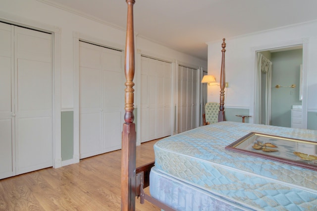 bedroom with crown molding, light wood-type flooring, and two closets