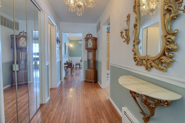 hallway featuring wood-type flooring, a baseboard heating unit, and a chandelier