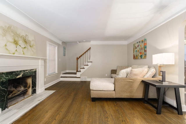 living room featuring crown molding, a fireplace, and dark hardwood / wood-style floors