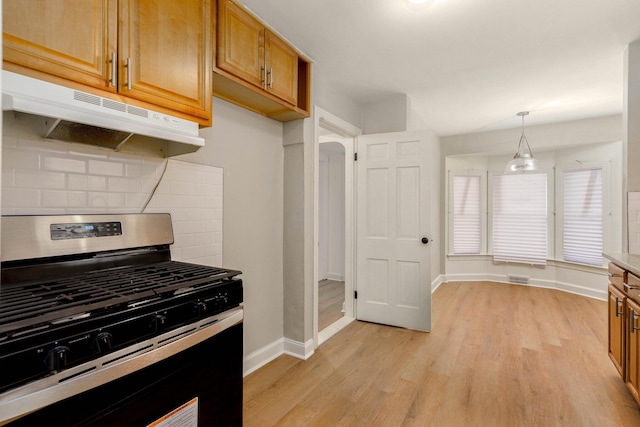 kitchen featuring stainless steel range with gas stovetop, decorative backsplash, light wood-type flooring, and decorative light fixtures