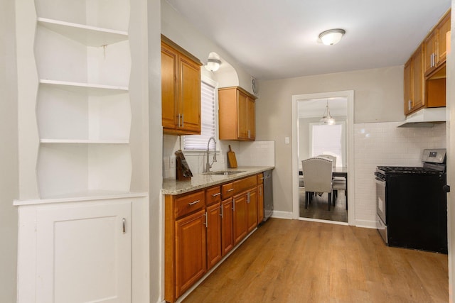 kitchen with sink, light hardwood / wood-style flooring, appliances with stainless steel finishes, light stone counters, and decorative backsplash