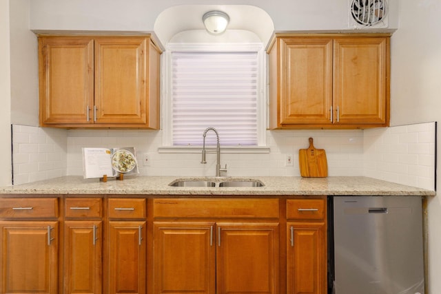 kitchen with stainless steel dishwasher, light stone countertops, sink, and backsplash