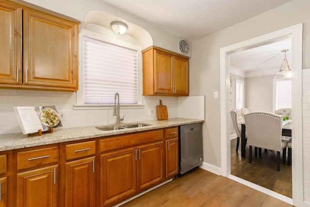 kitchen with backsplash, stainless steel dishwasher, sink, and light wood-type flooring