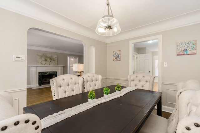 dining room featuring crown molding, hardwood / wood-style flooring, and a high end fireplace