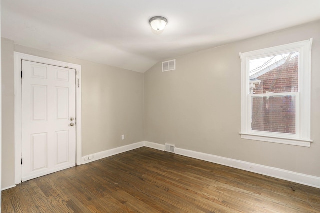 empty room with vaulted ceiling and dark hardwood / wood-style floors