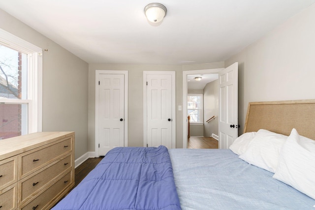 bedroom with multiple windows and dark hardwood / wood-style floors