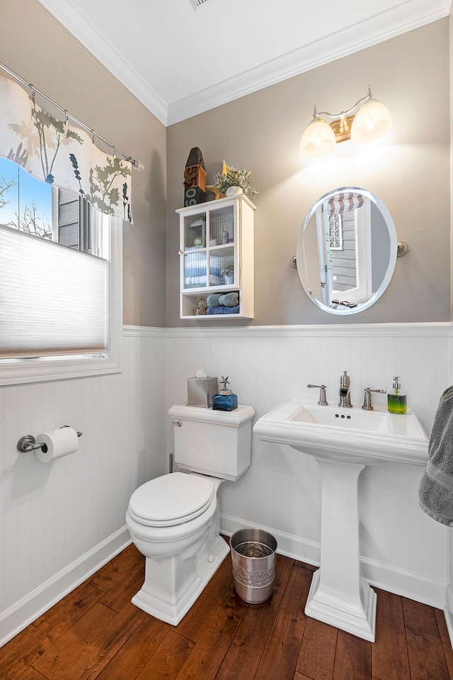 bathroom with toilet, hardwood / wood-style flooring, ornamental molding, and a wainscoted wall