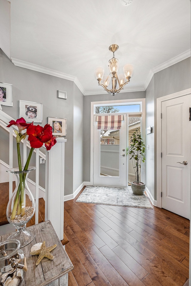 foyer with a chandelier, crown molding, baseboards, and hardwood / wood-style flooring