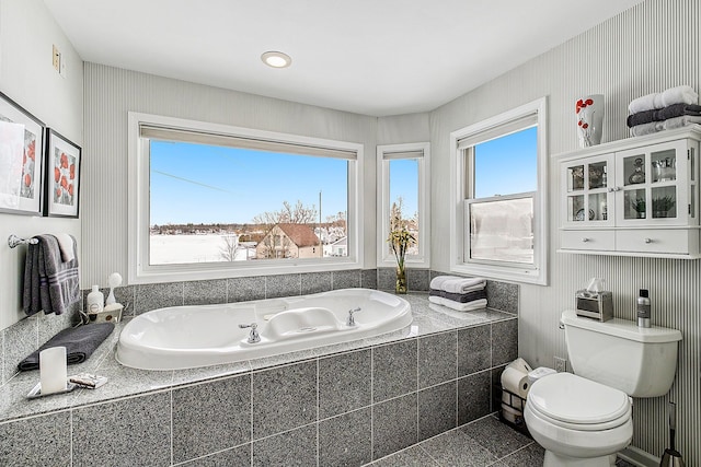 bathroom featuring a garden tub and toilet