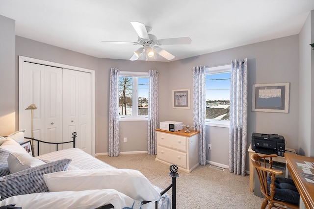 bedroom with light carpet, multiple windows, a closet, and baseboards