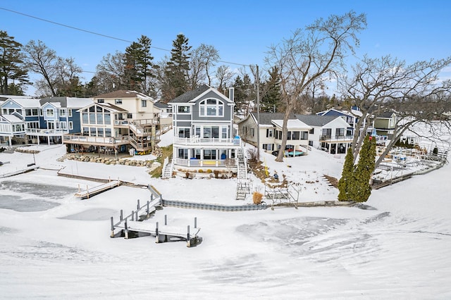 snow covered back of property featuring a residential view and stairs