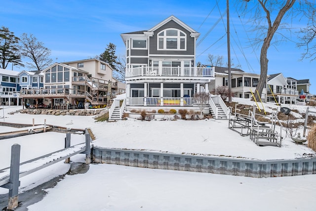 snow covered property with a balcony and stairs