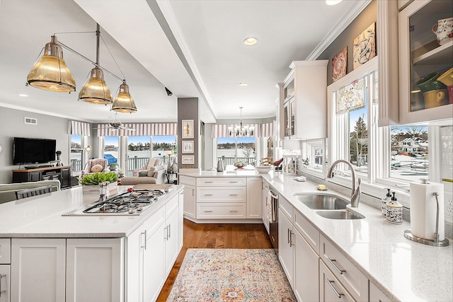 kitchen with crown molding, stainless steel gas cooktop, open floor plan, a sink, and a peninsula