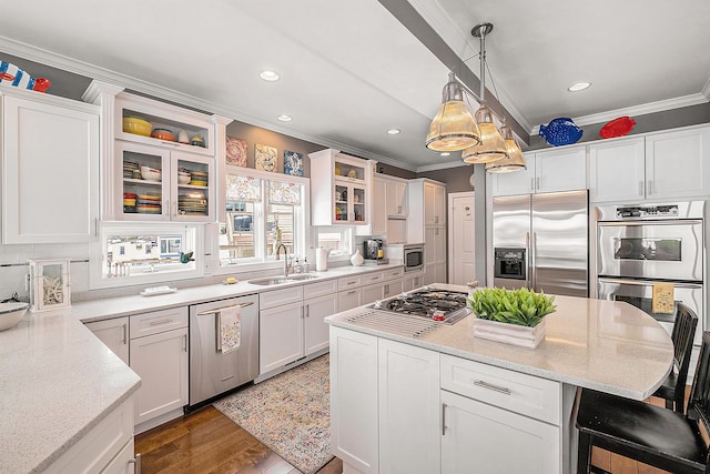 kitchen with stainless steel appliances, a sink, white cabinets, a kitchen bar, and crown molding