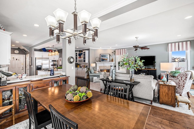 dining area featuring recessed lighting, ornamental molding, wood finished floors, and a glass covered fireplace