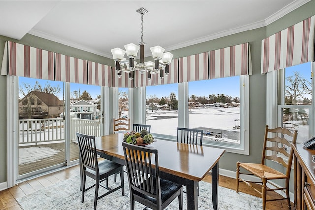 dining space featuring light wood finished floors, ornamental molding, baseboards, and a notable chandelier