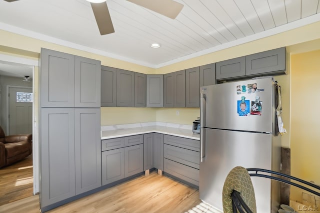 kitchen featuring light hardwood / wood-style flooring, gray cabinets, stainless steel refrigerator, ceiling fan, and ornamental molding