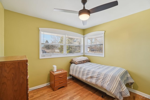 bedroom with ceiling fan, multiple windows, and light hardwood / wood-style flooring