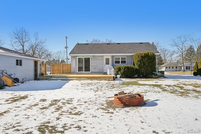 snow covered back of property with an outdoor fire pit