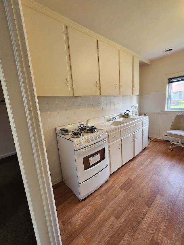 kitchen featuring sink, white gas stove, decorative backsplash, and light hardwood / wood-style flooring