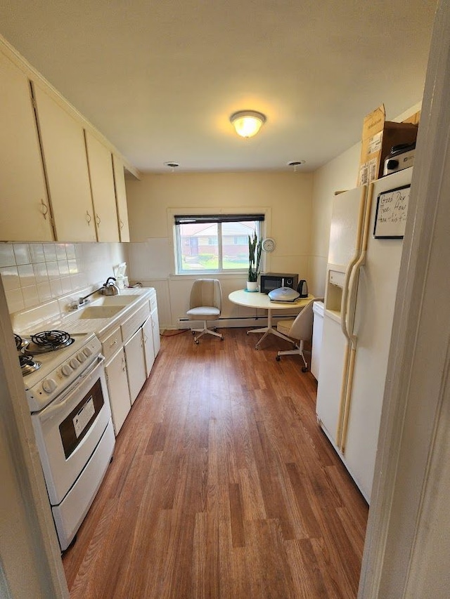 kitchen featuring sink, white appliances, hardwood / wood-style flooring, tasteful backsplash, and white cabinets