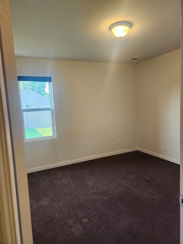 unfurnished room with dark colored carpet