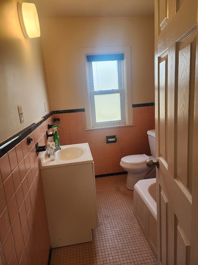 bathroom with tile patterned floors, vanity, toilet, and tile walls