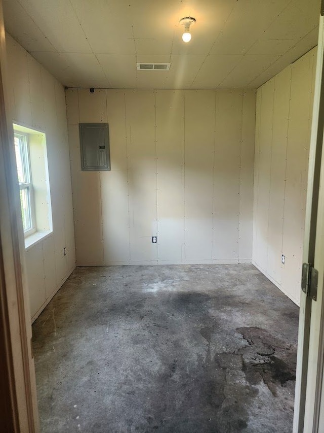 unfurnished room featuring electric panel and concrete floors