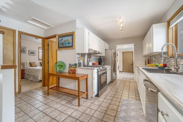 kitchen featuring sink, stainless steel appliances, white cabinets, light tile patterned flooring, and decorative backsplash