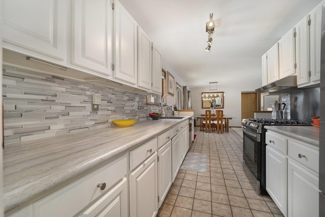 kitchen featuring sink, white cabinets, hanging light fixtures, light tile patterned floors, and gas stove