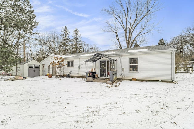 snow covered rear of property featuring a storage unit