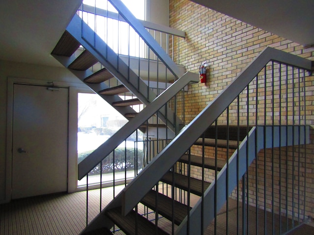 stairway featuring a high ceiling and brick wall