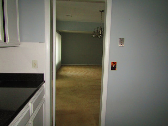 corridor featuring a chandelier and carpet floors