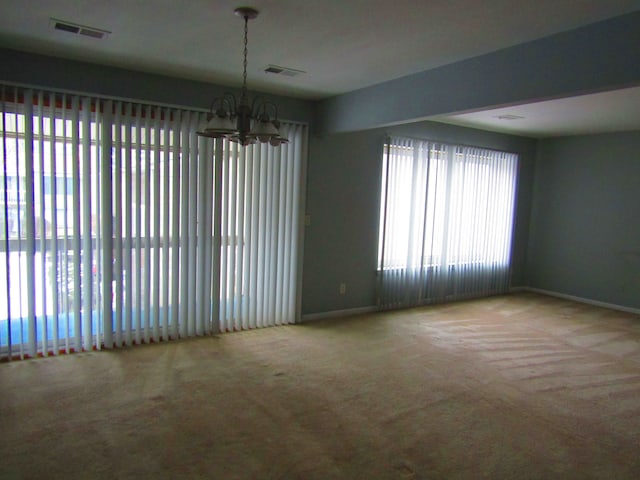 unfurnished room featuring light carpet and a notable chandelier