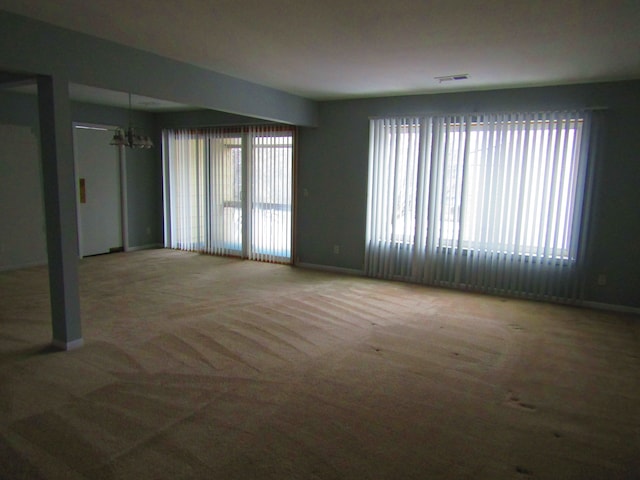 empty room featuring carpet floors and a notable chandelier