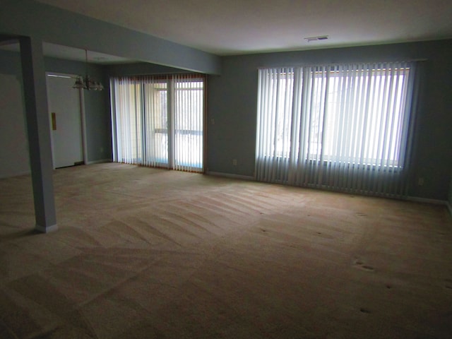 spare room featuring a chandelier and carpet