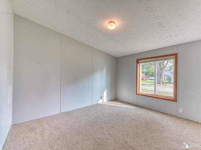 carpeted empty room with a textured ceiling