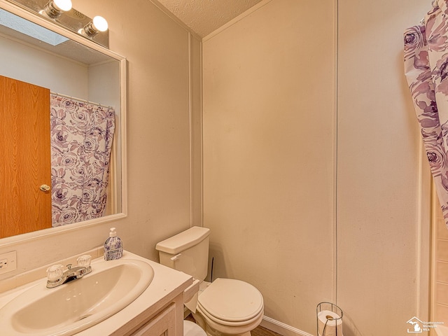 bathroom with vanity, toilet, and a textured ceiling