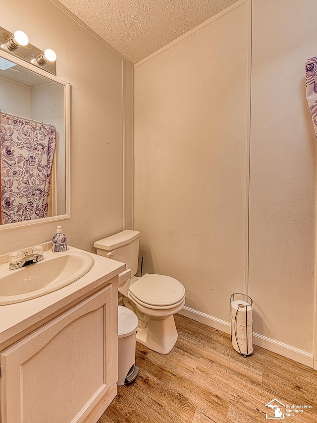 bathroom featuring vanity, hardwood / wood-style floors, a textured ceiling, and toilet