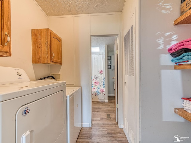 washroom with washing machine and dryer, cabinets, and a textured ceiling