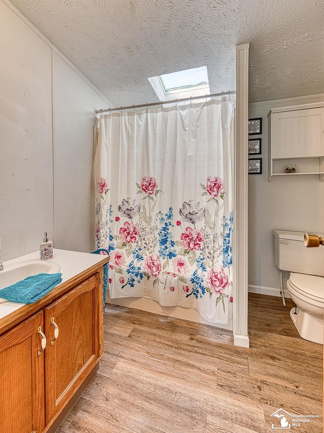 full bathroom with hardwood / wood-style floors, shower / bath combination with curtain, a textured ceiling, and a skylight