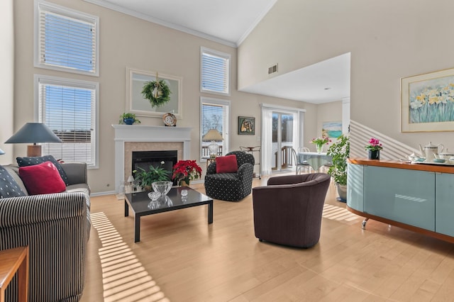 living room featuring ornamental molding, a towering ceiling, and light hardwood / wood-style floors