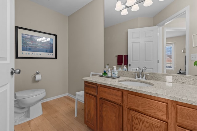 bathroom featuring vanity, a notable chandelier, wood-type flooring, and toilet