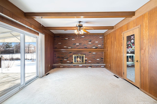 unfurnished living room featuring beam ceiling, a fireplace, light colored carpet, and wooden walls