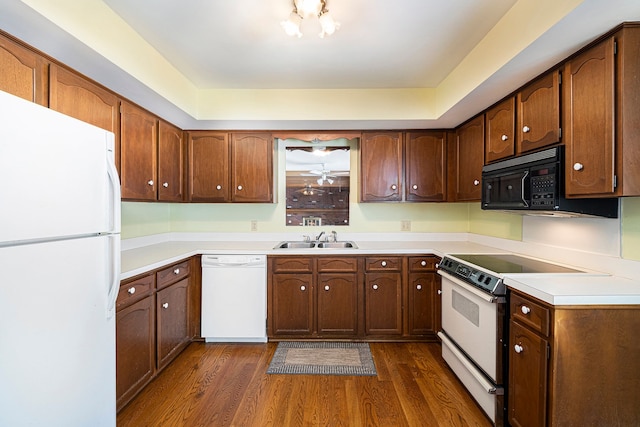 kitchen featuring white appliances, dark hardwood / wood-style flooring, and sink