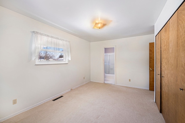 unfurnished bedroom with light colored carpet and a closet